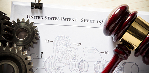 Metal gears and a gavel on top of a U.S. patent document