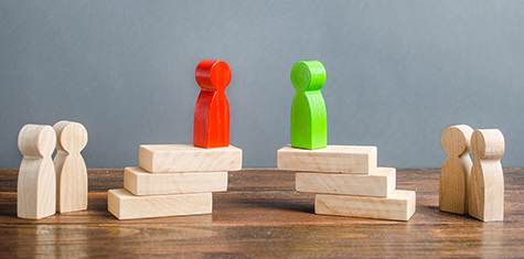 Red and green wooden figurines on raised platforms amidst other figurines