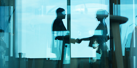 Two people shaking hands viewed through a window