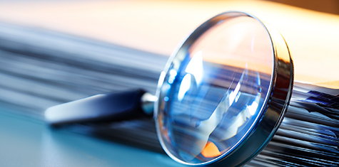 Magnifying glass next to manila folder full of files