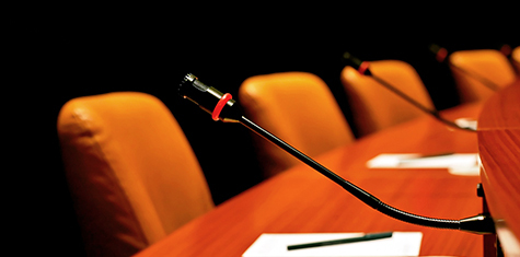 Conference table with microphones and empty chairs