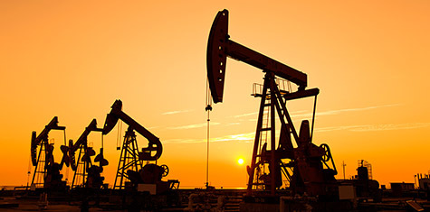 Row of oil derricks at sunset