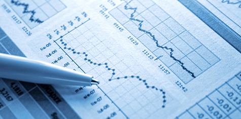 Pen on top of investment reports with graphs