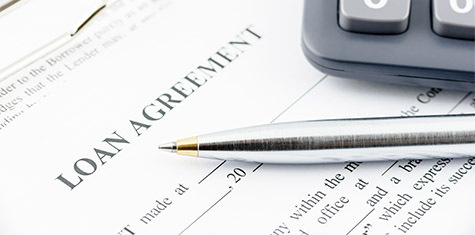 Close up of loan agreement paperwork, pen, and calculator